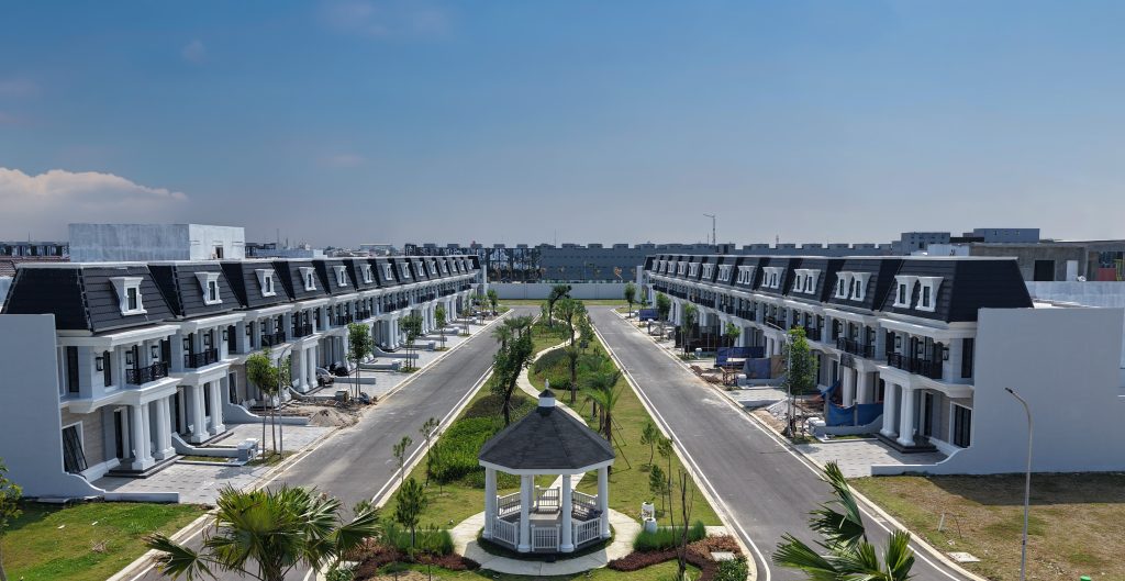 Aerial view of a modern townhouse development with two parallel rows of white buildings and a central gazebo.