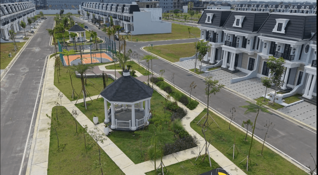 Aerial view of a modern residential neighborhood with white townhomes, a central gazebo, and a small basketball court in the park area.